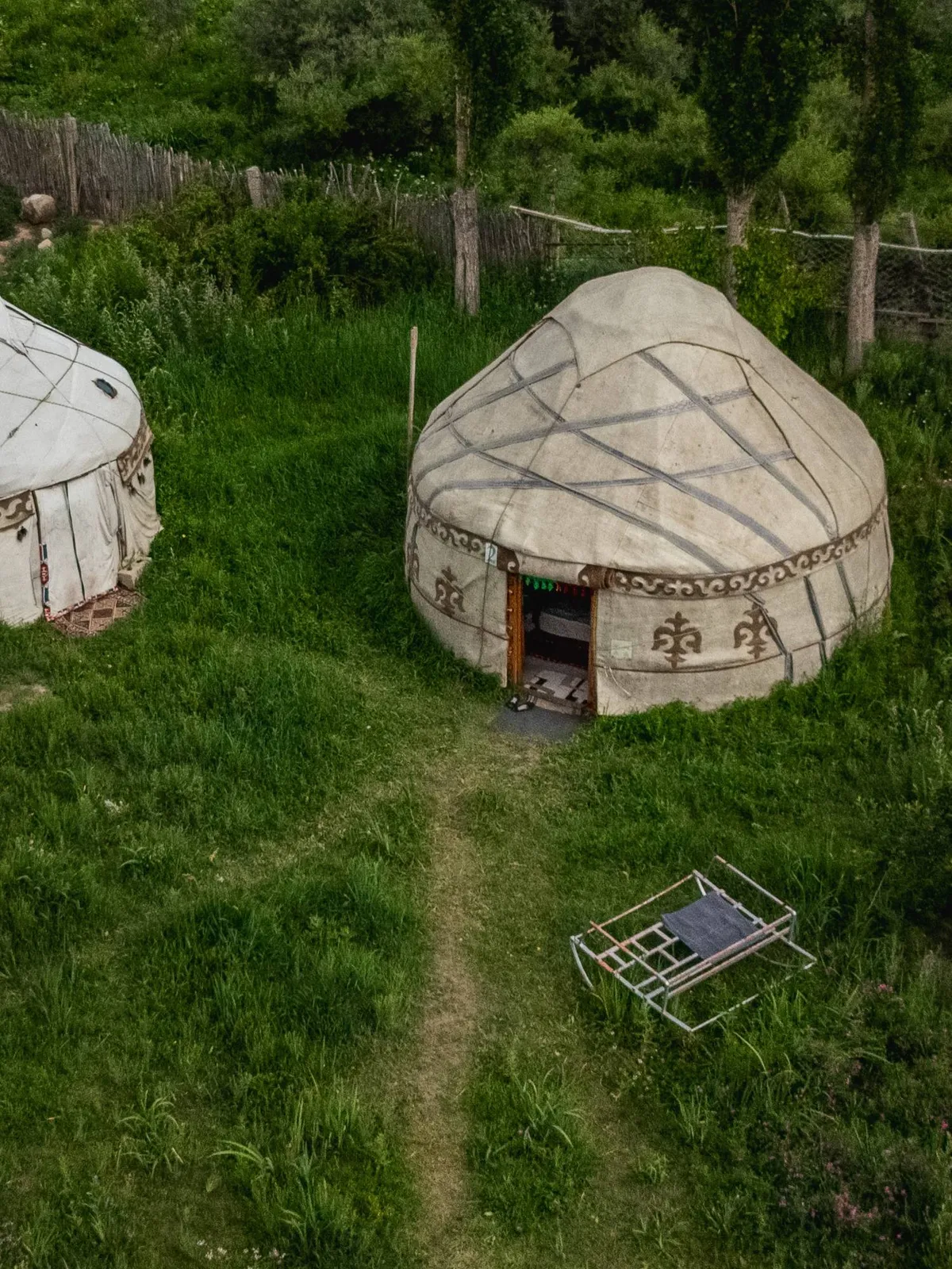 Two yurts on the grass by the trees, seen from above